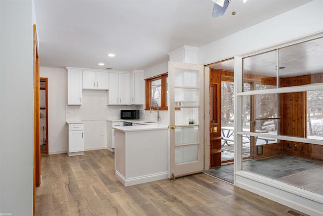 kitchen with white cabinetry, sink, hardwood / wood-style floors, and decorative backsplash