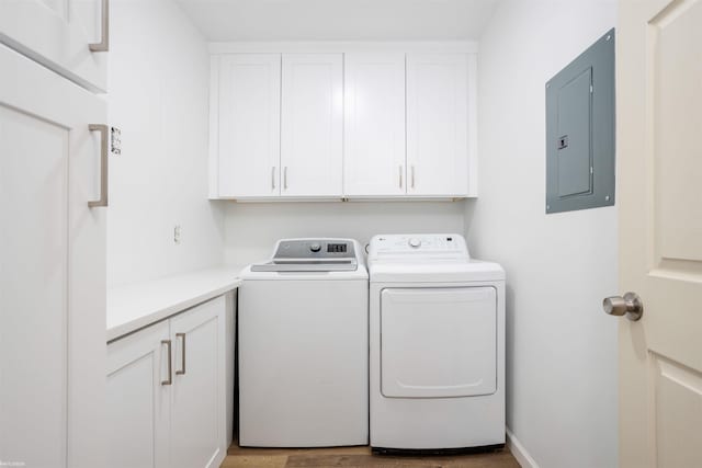 clothes washing area with cabinets, electric panel, washer and clothes dryer, and light hardwood / wood-style floors