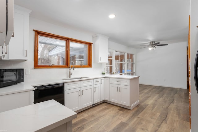 kitchen featuring sink, white cabinetry, light hardwood / wood-style flooring, kitchen peninsula, and black appliances