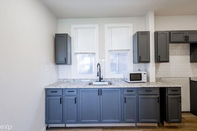 kitchen featuring light stone counters, sink, wood-type flooring, and tasteful backsplash