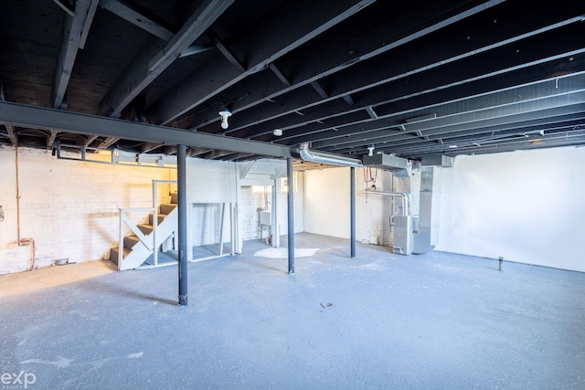 basement with heating unit, sink, and brick wall