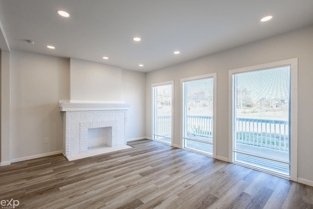 unfurnished living room featuring a brick fireplace and light wood-type flooring