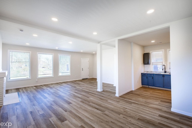 unfurnished living room featuring sink and light hardwood / wood-style flooring