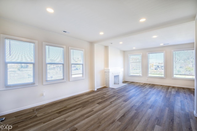 unfurnished living room featuring dark wood-type flooring and a fireplace