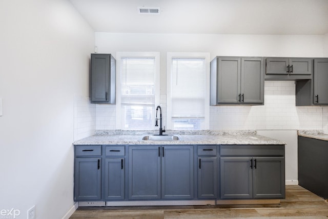 kitchen featuring gray cabinets, sink, hardwood / wood-style floors, and backsplash