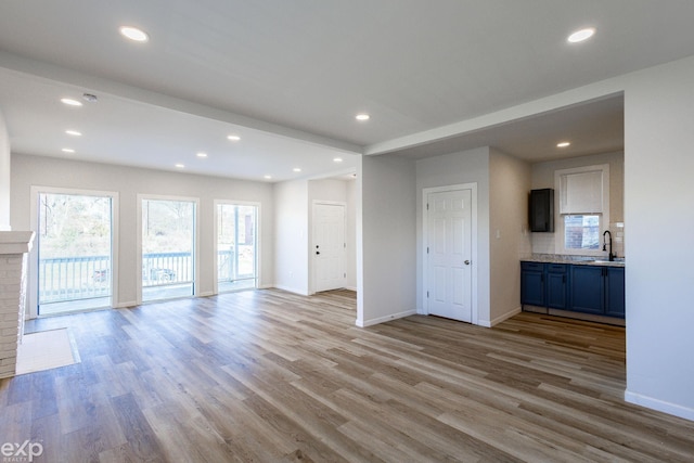 unfurnished living room featuring sink and light hardwood / wood-style floors