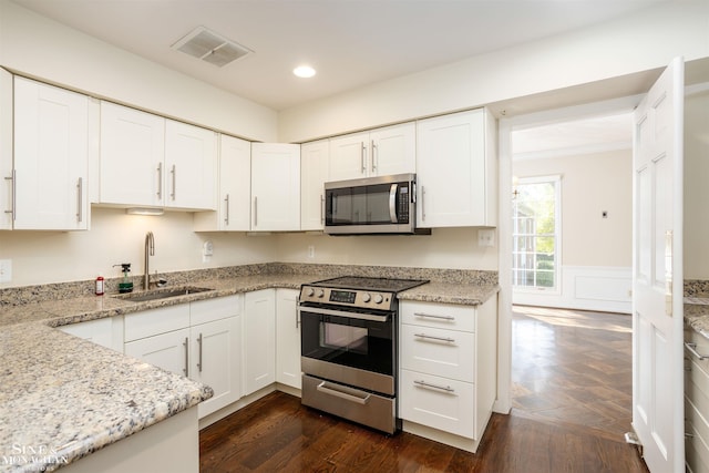 kitchen featuring sink, dark hardwood / wood-style floors, stainless steel appliances, light stone countertops, and white cabinets