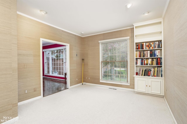 carpeted empty room with ornamental molding and built in shelves