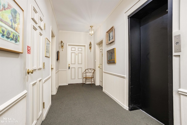 corridor with elevator, ornamental molding, and dark carpet