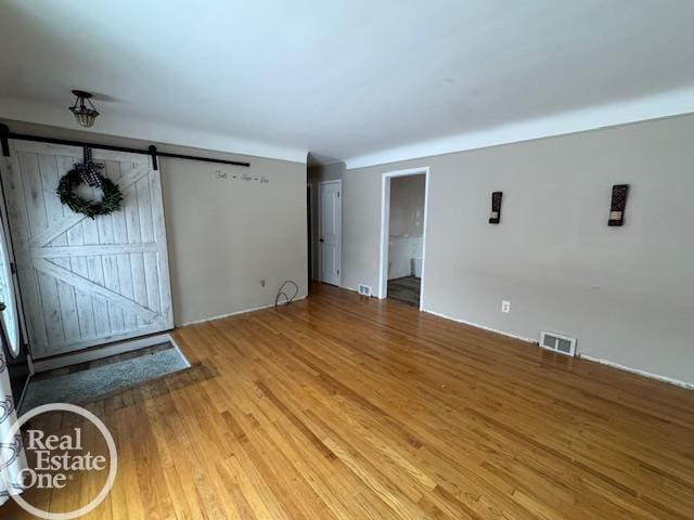 unfurnished living room featuring wood-type flooring and a barn door