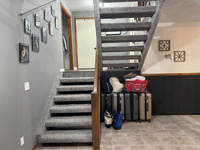 stairs with tile patterned flooring and a textured ceiling