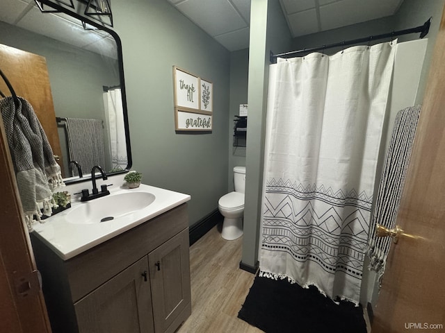 bathroom featuring vanity, wood-type flooring, a paneled ceiling, and toilet