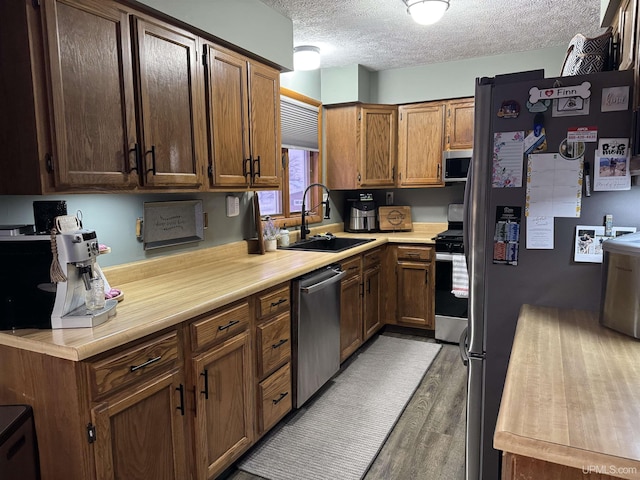 kitchen featuring stainless steel appliances, dark hardwood / wood-style flooring, sink, and a textured ceiling