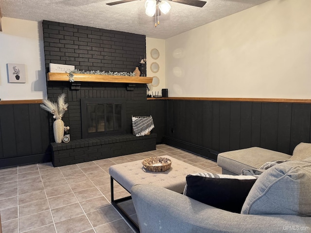 living room with light tile patterned flooring, ceiling fan, a fireplace, and a textured ceiling