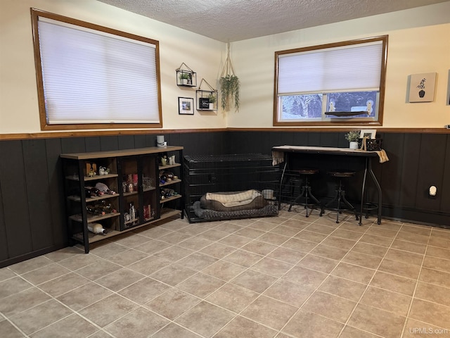 interior space with light tile patterned flooring, wooden walls, and a textured ceiling