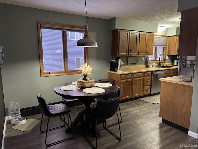 kitchen featuring dark hardwood / wood-style floors, pendant lighting, dishwasher, sink, and a textured ceiling