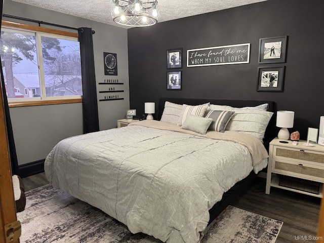 bedroom featuring wood-type flooring, a textured ceiling, and a notable chandelier