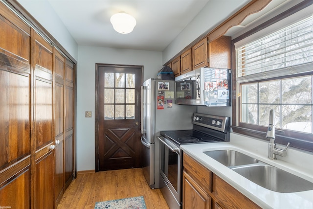 kitchen with sink, stainless steel appliances, and light wood-type flooring