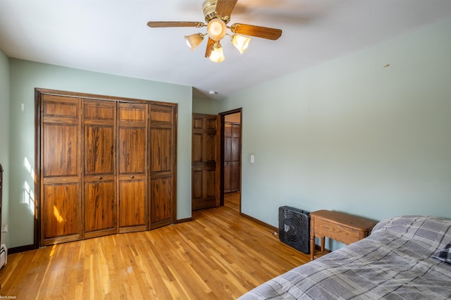 bedroom with a baseboard heating unit, a closet, ceiling fan, and light hardwood / wood-style flooring