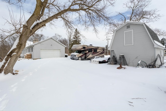 view of snowy exterior with a garage and an outdoor structure