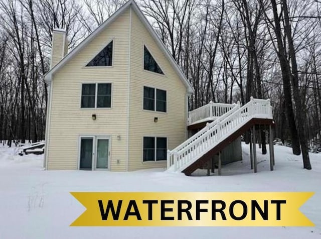 snow covered rear of property featuring a deck