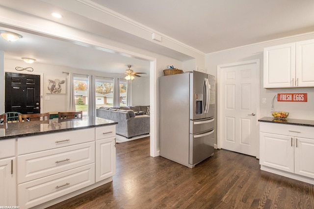 kitchen featuring dark hardwood / wood-style flooring, stainless steel fridge, ornamental molding, dark stone counters, and white cabinets