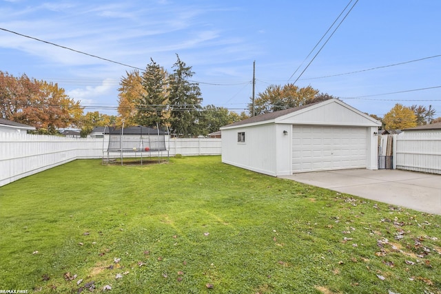 view of yard with a trampoline, a garage, and an outdoor structure