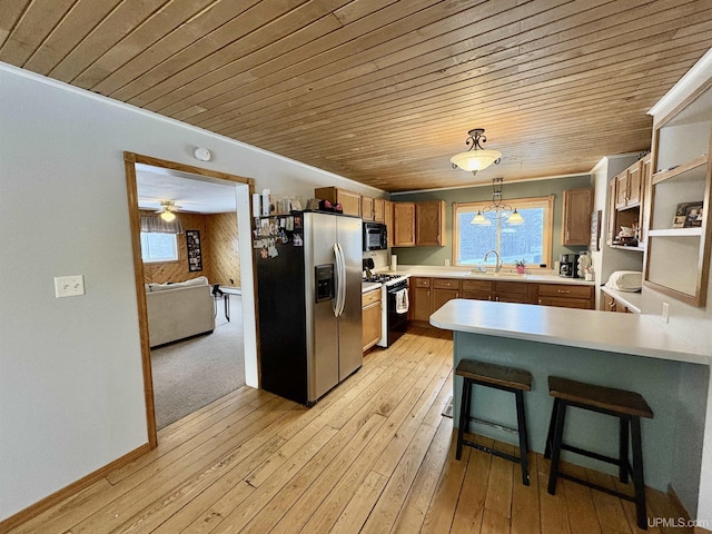 kitchen featuring light hardwood / wood-style flooring, sink, stainless steel refrigerator with ice dispenser, gas range oven, and hanging light fixtures