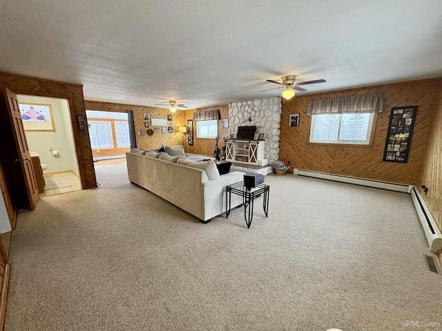 carpeted living room with wood walls, a wood stove, and a textured ceiling