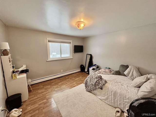 bedroom featuring hardwood / wood-style flooring and a baseboard heating unit