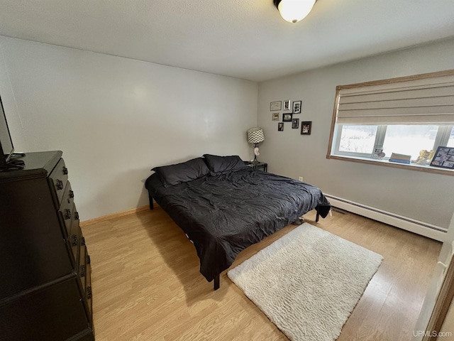 bedroom with light wood-type flooring and baseboard heating