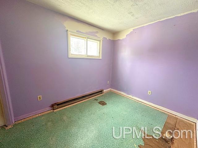 empty room with baseboard heating and a textured ceiling