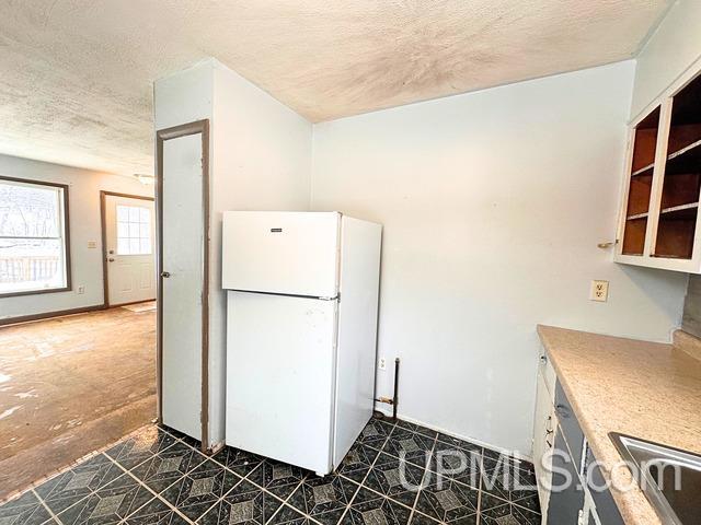 kitchen with white refrigerator, sink, washer / clothes dryer, and a textured ceiling