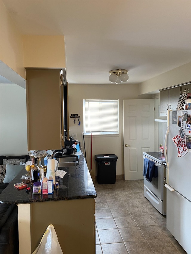 kitchen featuring white appliances, light tile patterned floors, sink, and kitchen peninsula