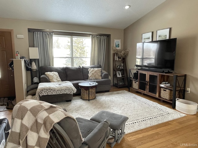 living room featuring hardwood / wood-style flooring, vaulted ceiling, and a textured ceiling