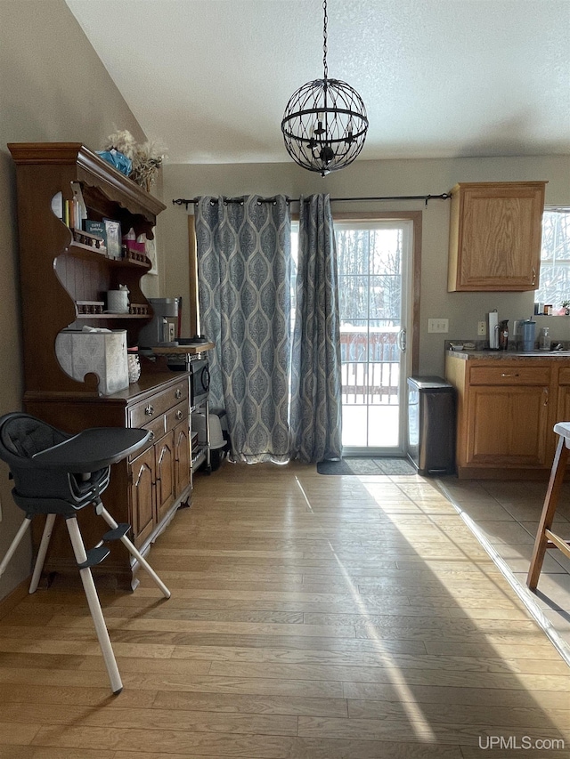 dining space with plenty of natural light, light hardwood / wood-style floors, and an inviting chandelier