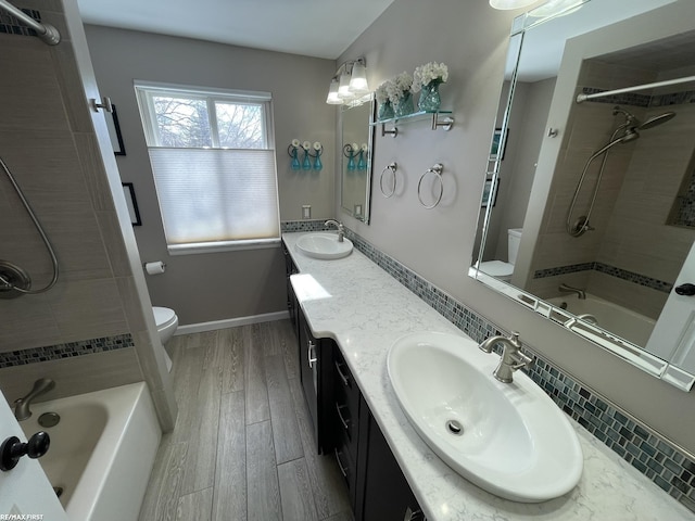 full bathroom featuring hardwood / wood-style flooring, tiled shower / bath combo, vanity, and toilet