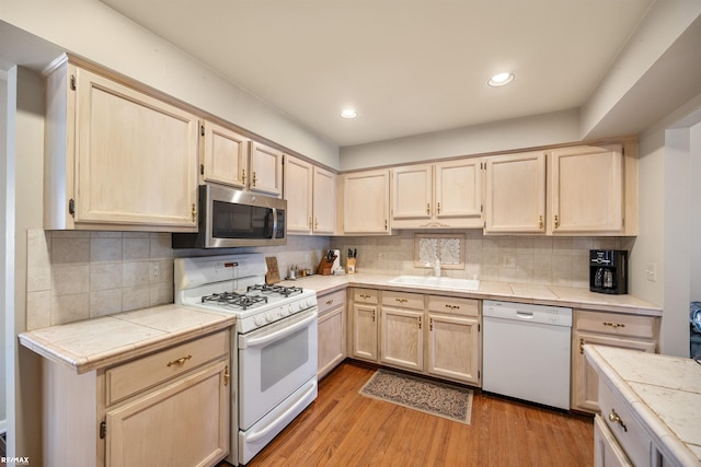 kitchen featuring tile counters, light hardwood / wood-style flooring, sink, white appliances, and light brown cabinets