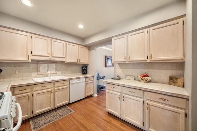 kitchen with light hardwood / wood-style flooring, tile countertops, white appliances, backsplash, and sink