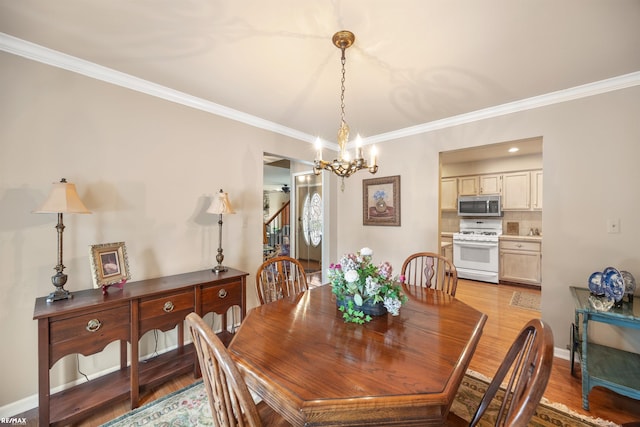 dining room with light wood-type flooring, ornamental molding, and a notable chandelier