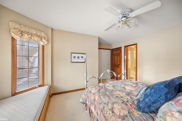 bedroom featuring ensuite bathroom, light colored carpet, and ceiling fan