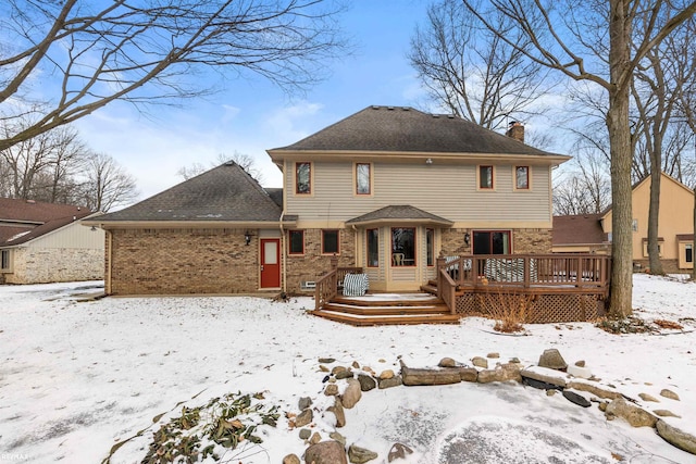 snow covered back of property with a wooden deck