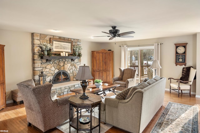 living room featuring light hardwood / wood-style floors, ceiling fan, and a fireplace