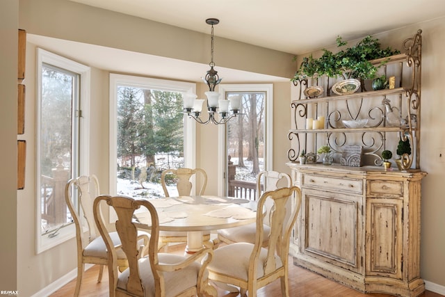 dining area with light hardwood / wood-style flooring and an inviting chandelier