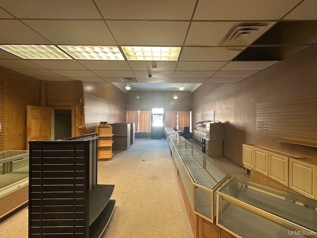 interior space with a paneled ceiling and light carpet