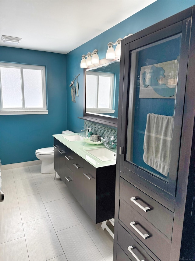 bathroom with toilet, vanity, and tasteful backsplash