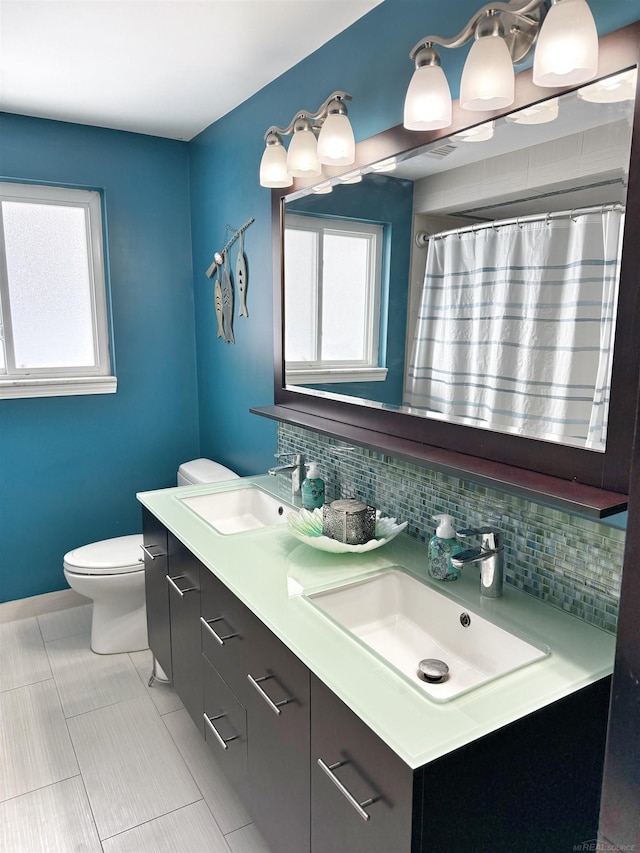 bathroom with toilet, tile patterned flooring, vanity, and decorative backsplash