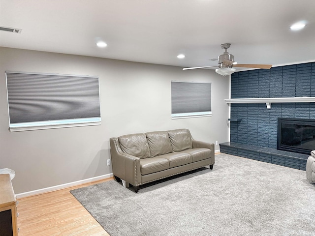 living room featuring a fireplace, ceiling fan, and wood-type flooring