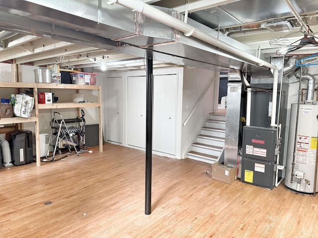 basement featuring heating unit, hardwood / wood-style flooring, and gas water heater