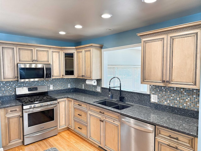 kitchen featuring sink, appliances with stainless steel finishes, dark stone countertops, and light hardwood / wood-style floors